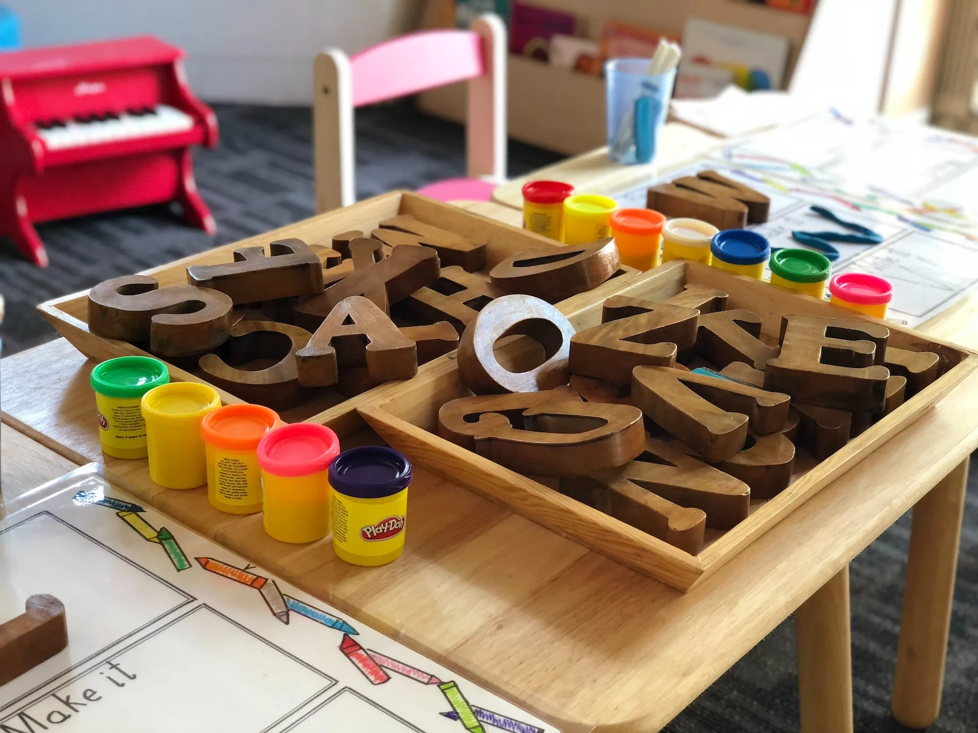 playdough containers with tray of letters and numbers on a table