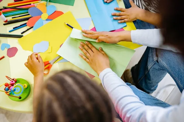 teacher and students folding colorful paper together